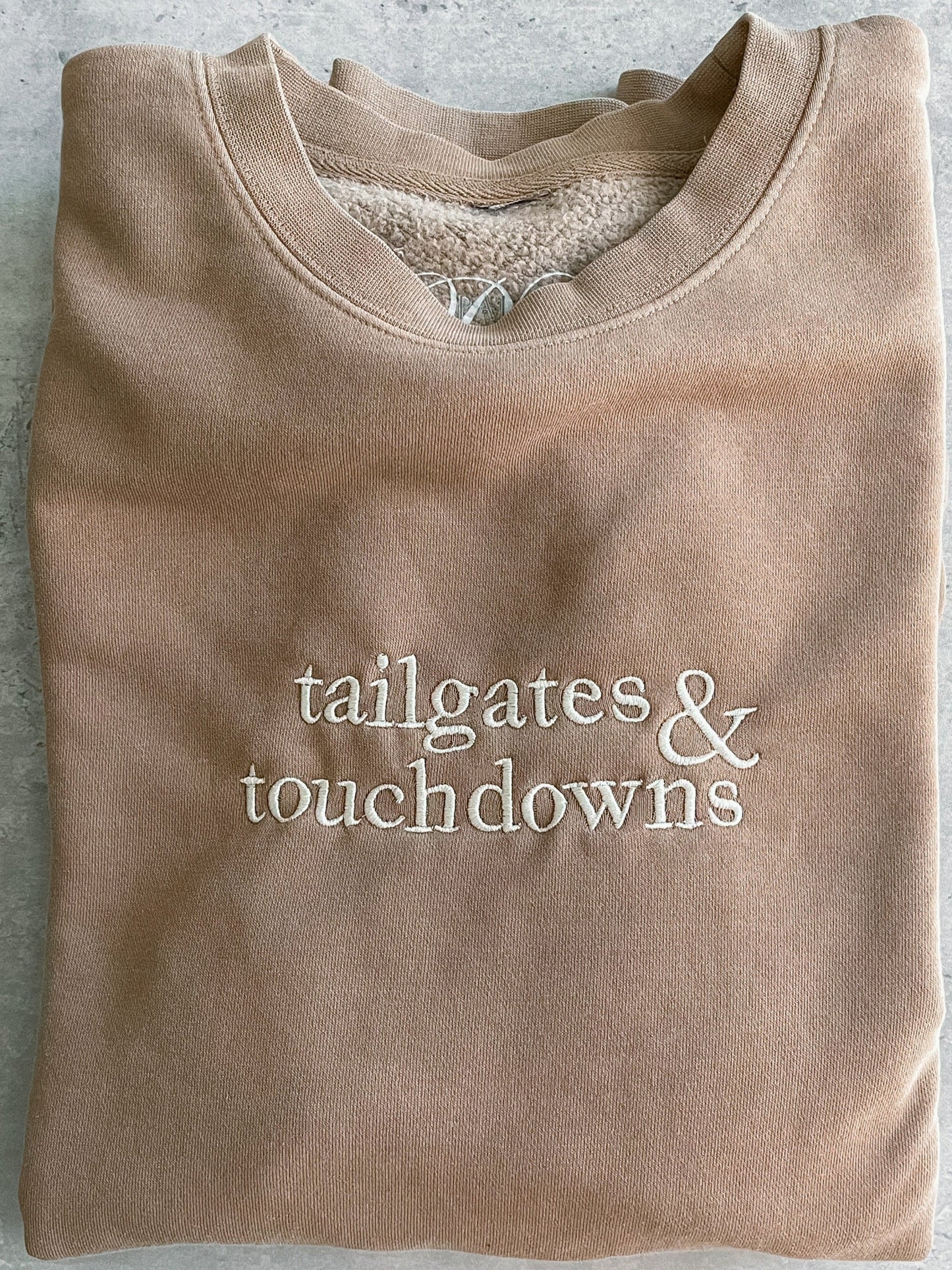 crewneck sweatshirt with embroidered text "tailgates & touchdowns"